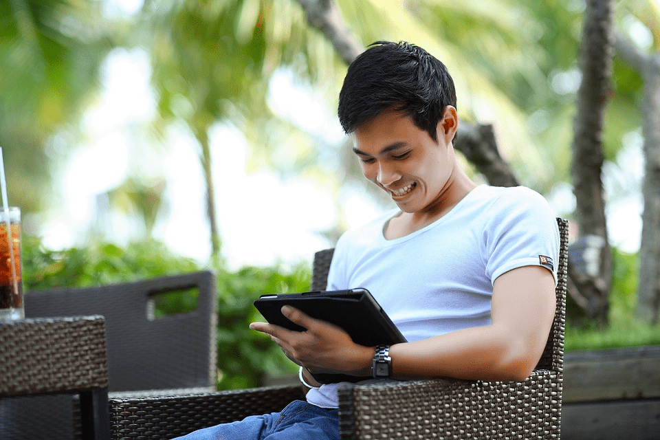 A person reading content on a tablet and smiling